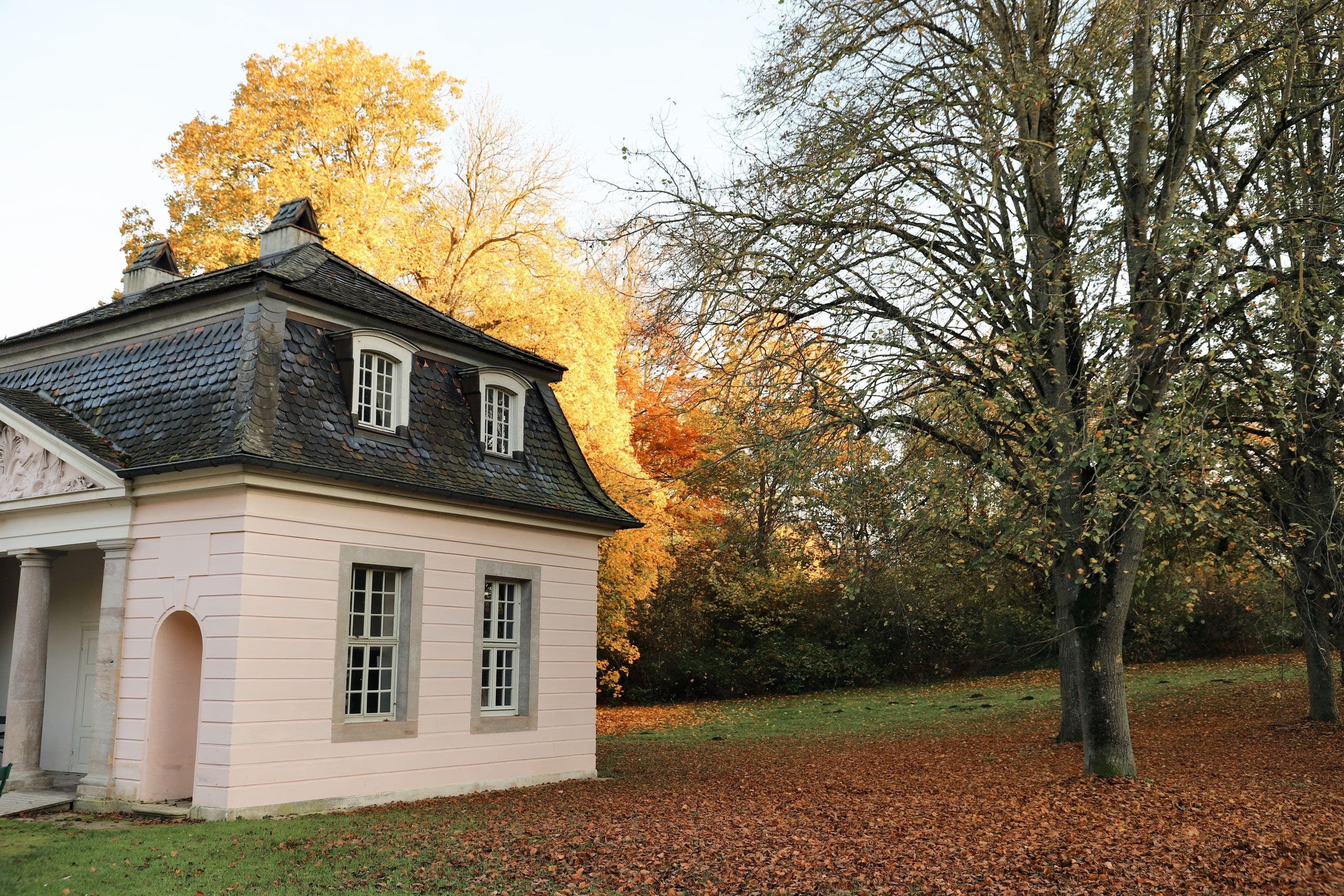 Pavillon im Park, Herbstlaub auf dem Rasen